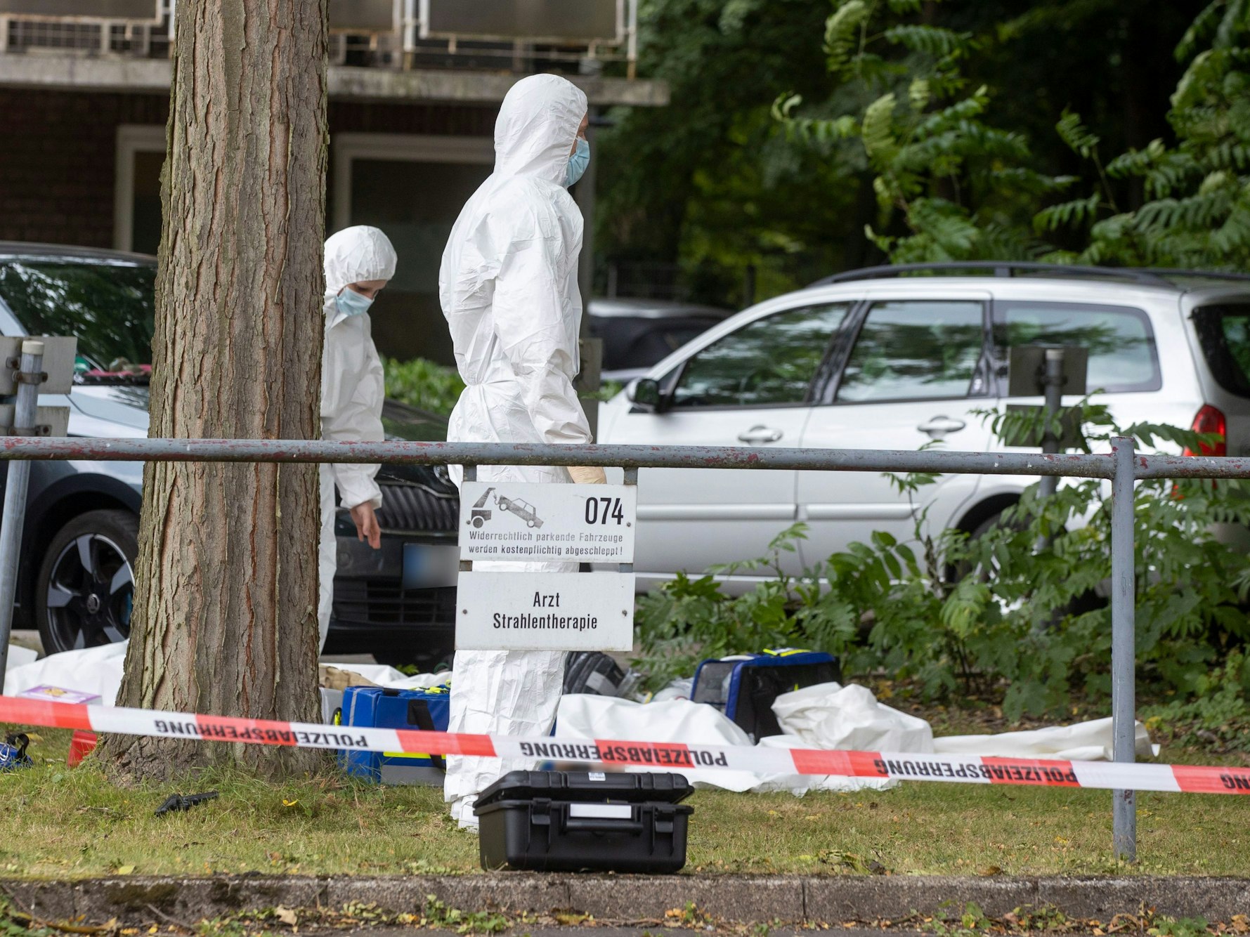 Mitarbeiter der Spurensicherung sind auf einem Gelände, das mit Flatterband der Polizei abgesperrt ist.