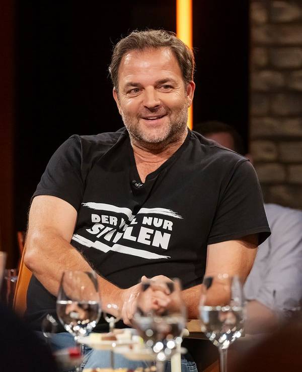 Martin Rütter sitzt auf einem Stuhl. Vor ihm stehen mehrere Gläser auf einem Tisch.