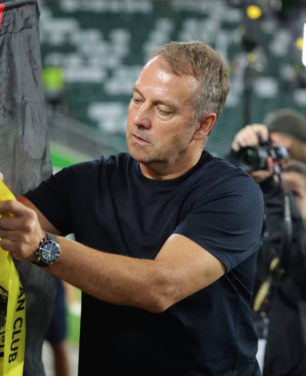 Hansi Flick unterschreibt auf der Deutschland-Flagge eines Fans.