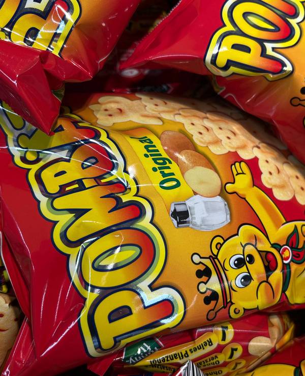 Mehrere Packungen der Chipsmarke Pom-Bär liegen übereinander.