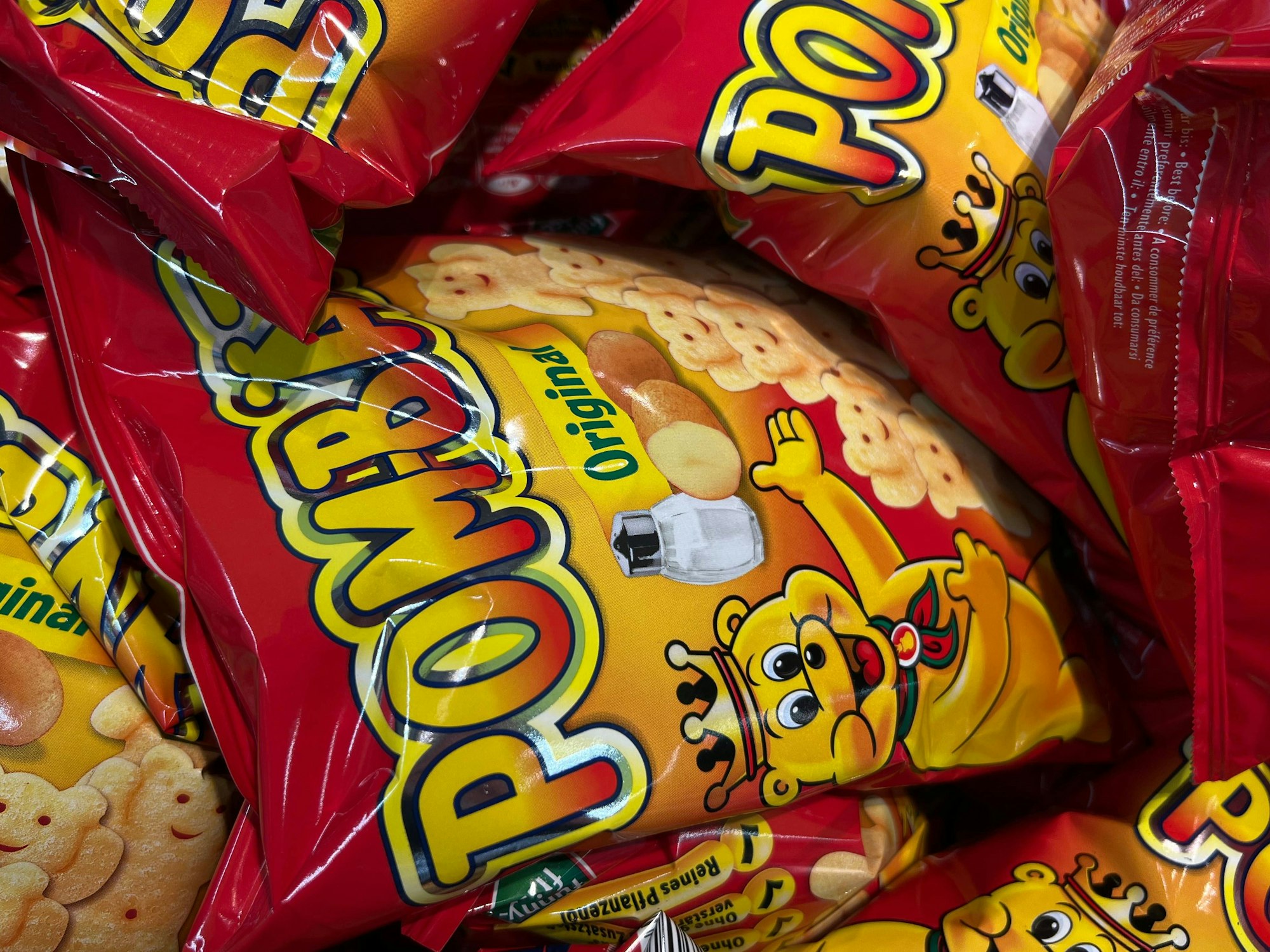 Mehrere Packungen der Chipsmarke Pom-Bär liegen übereinander.