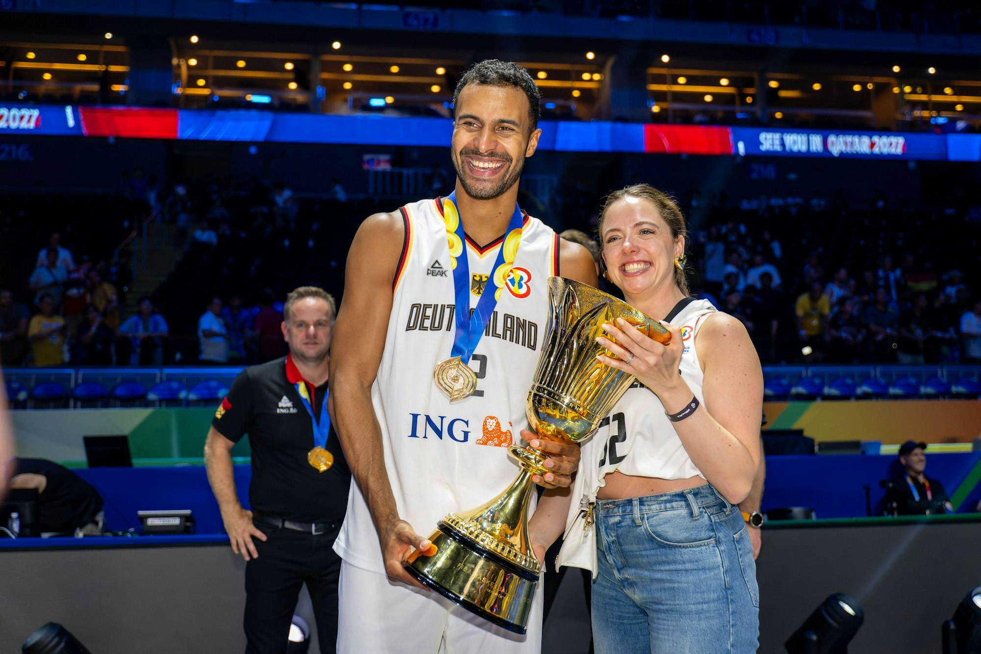 Marie hält den Pokal oben fest, Johannes Thiemann am Sockel.