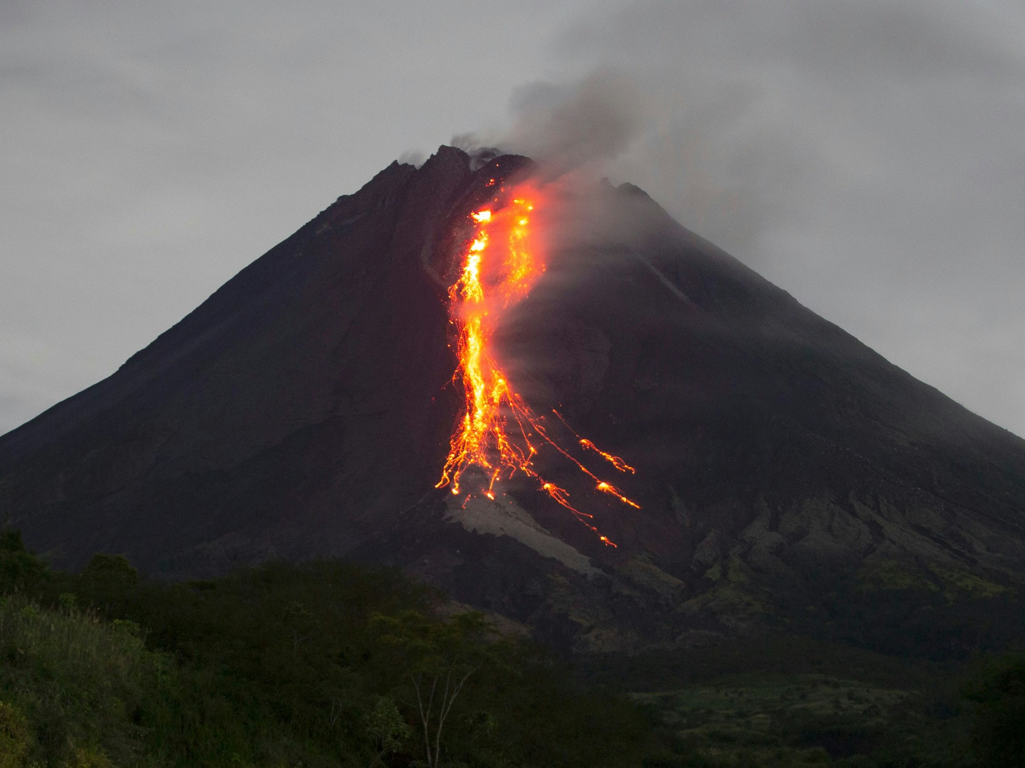 Ein Vulkankrater, aus dem glühende Magma hinausläuft.