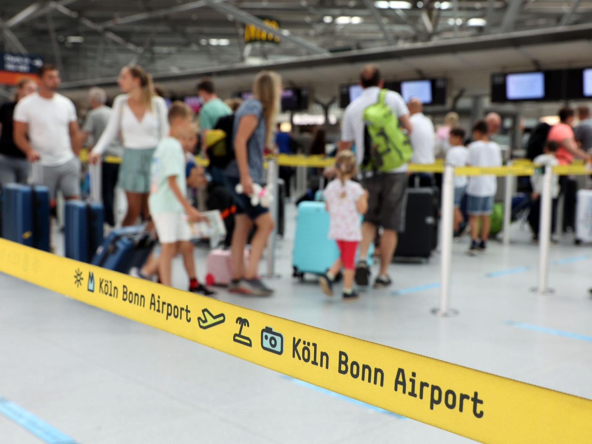 Menschen warten in einer Schlange am Flughafen Köln/Bonn auf den Check-in.