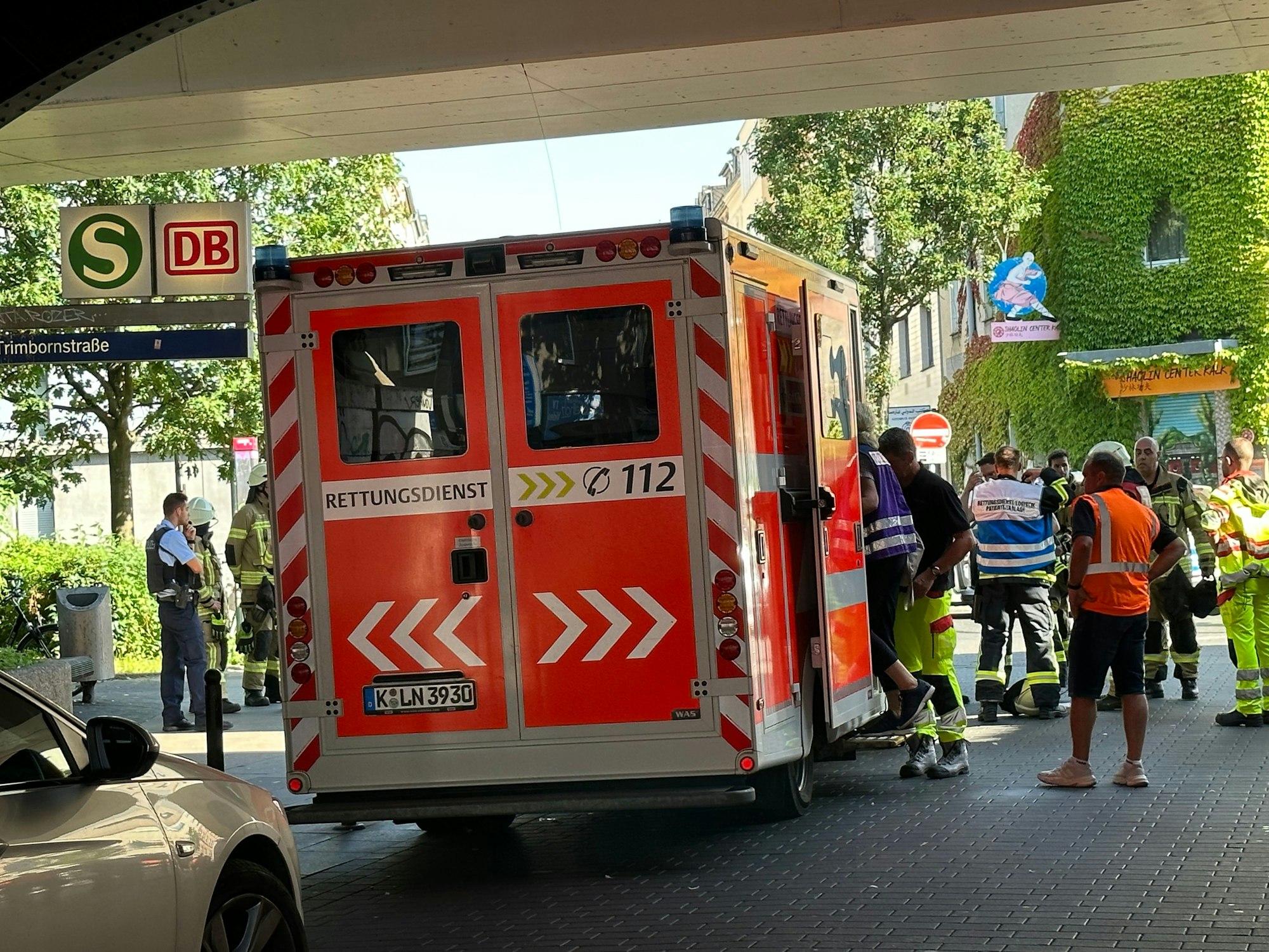 Ein Rettungswagen steht unter einer Bahnunterführung, Schilder weisen darauf hin, dass dort die Bahnhaltestelle Trimbornstraße ist.