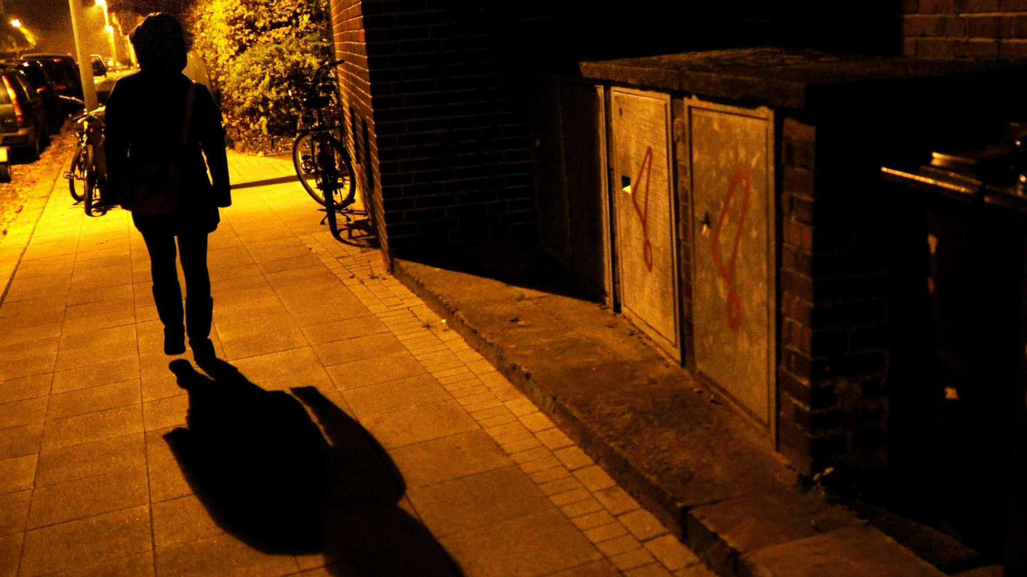 Eine Frau geht im Licht der Straßenlaternen über eine Straße
