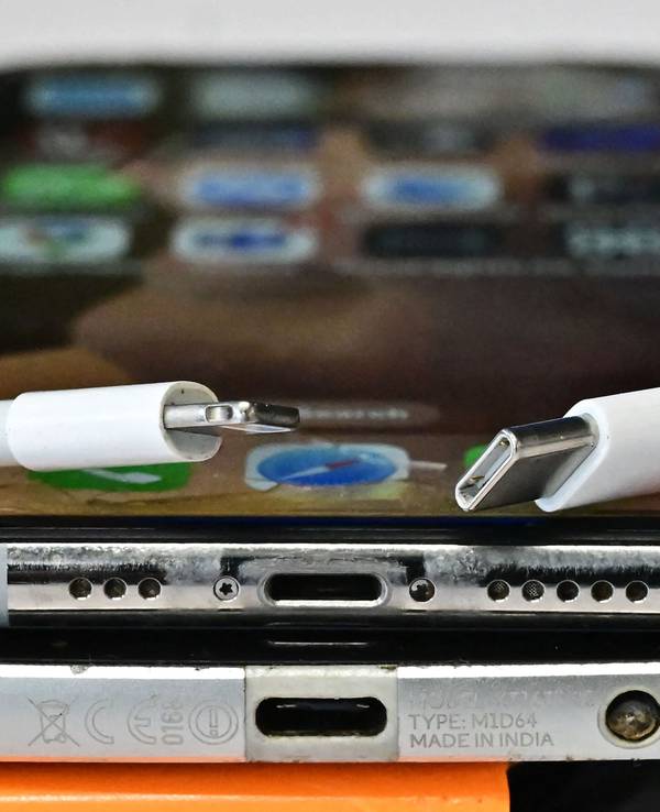 Ein USB-C-Ladegerät (rechts) und ein herkömmliches Apple-Lightning-Ladegerät sind an einem Apple iPhone mit Lightning-Anschluss über einem Android-Telefon mit USB-C-Anschluss zu sehen.