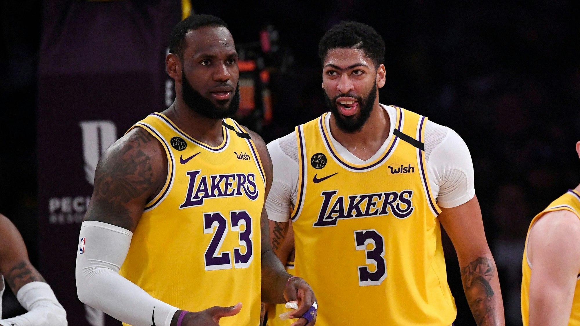 Zwei Spieler stehen im gelben Trikot der LA Lakers nebeneinander auf dem Spielfeld.