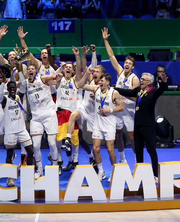 Die deutsche Nationalmannschaft im Basketball feiert mit dem WM-Pokal auf der Bühne.
