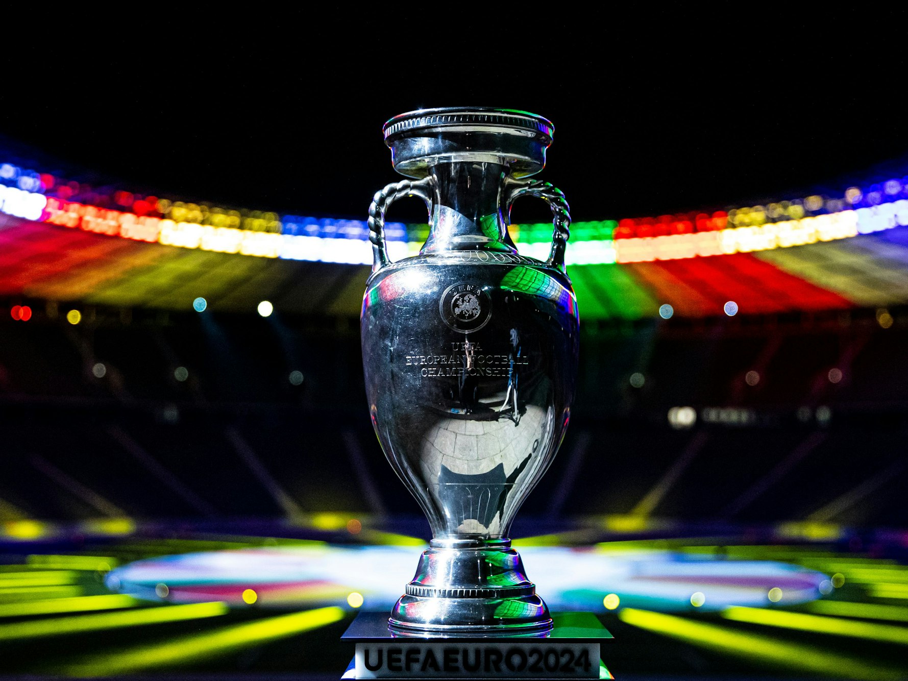 Der Siegerpokal der Fußball-Europameisterschaft 2024 steht im bunt erleuchteten Olympiastadion in Berlin.