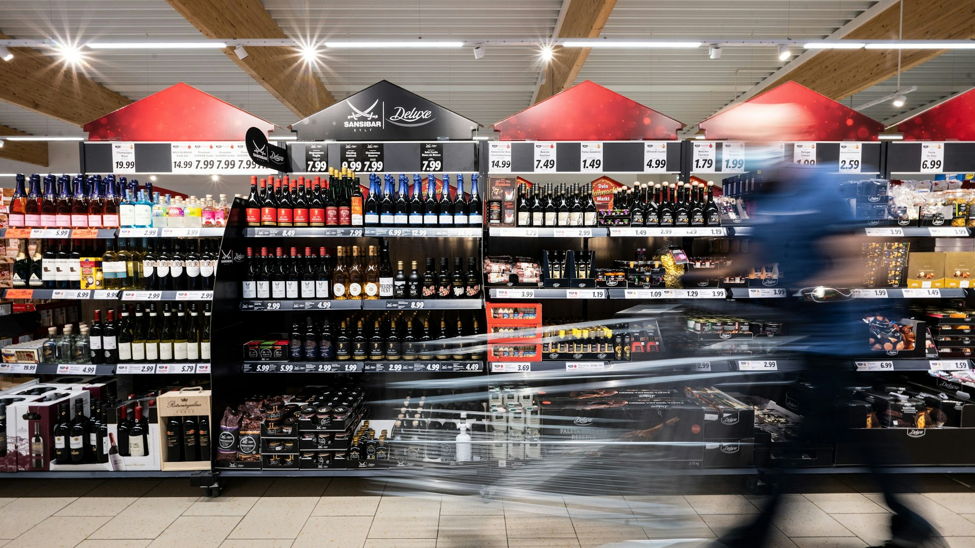 Ein Mann geht mit seinem Einkaufswagen in einer Lidl-Filiale an Regalen vorbei.