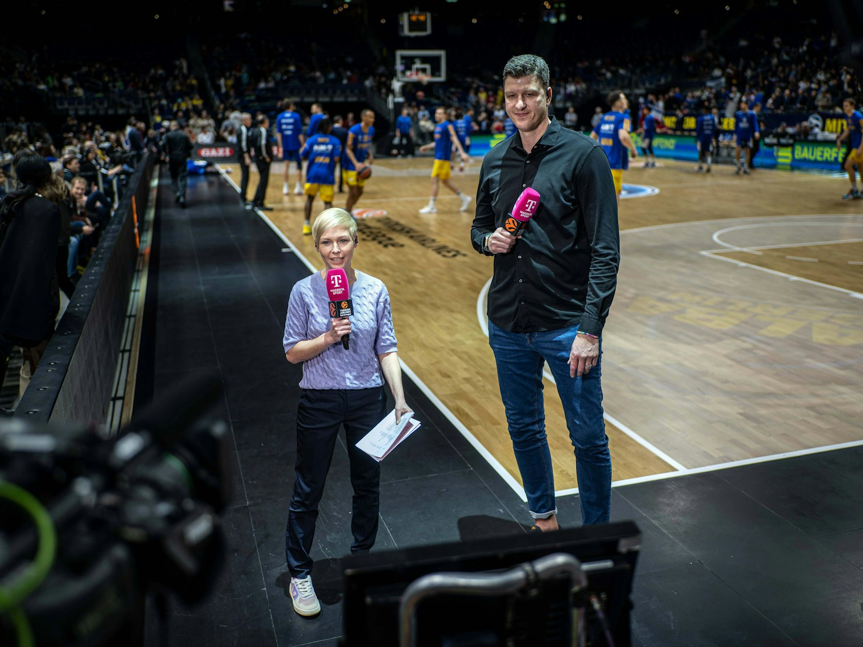 Anett Sattler steht neben einem Basketballer.