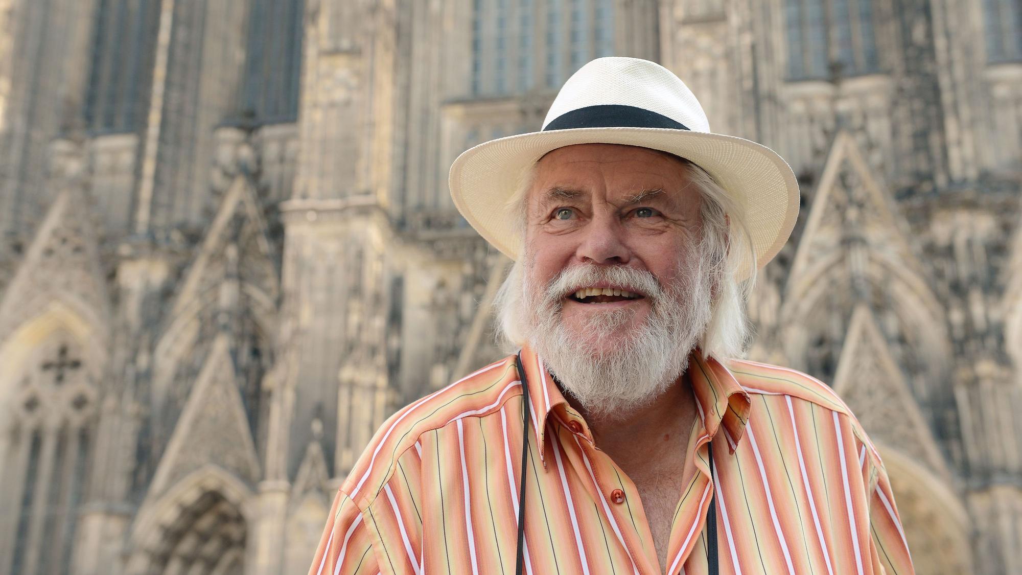 Sänger „King Size Dick“ steht mit Hut auf dem Kopf vor dem Kölner Dom.