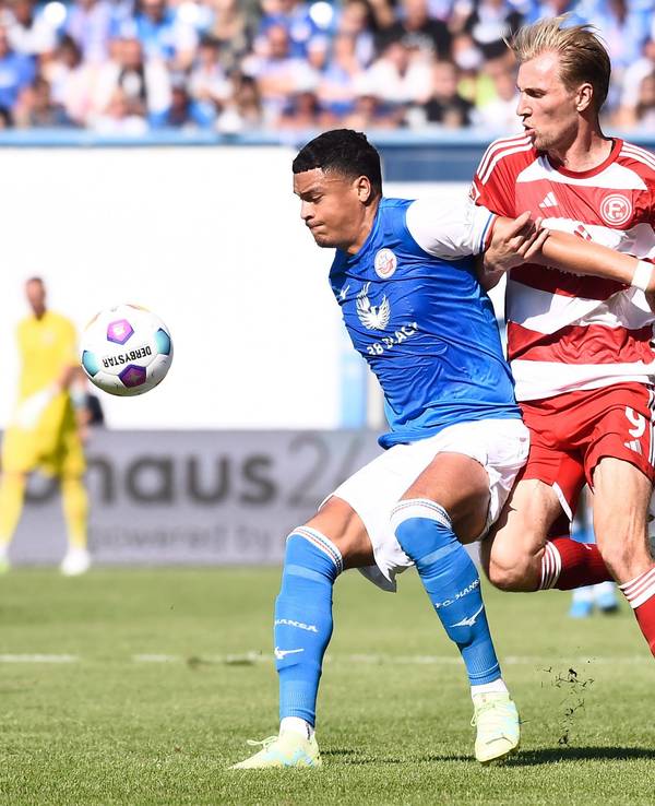 Rostocks Jonas David (l) behauptet den Ball gegen Düsseldorfs Vincent Vermeij im Mittelfeld.
