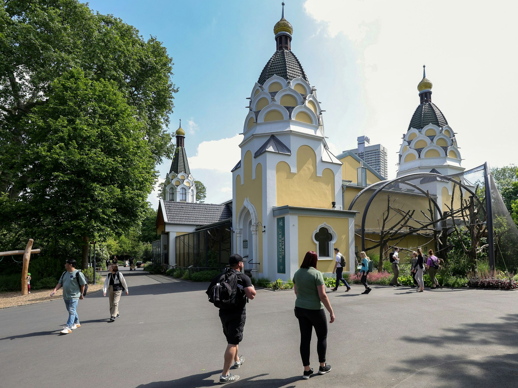 Blick auf das gelbe Arnulf-und-Elisabeth-Reichert-Haus im Kölner Zoo, davor einige Besucherinnen und Besucher.