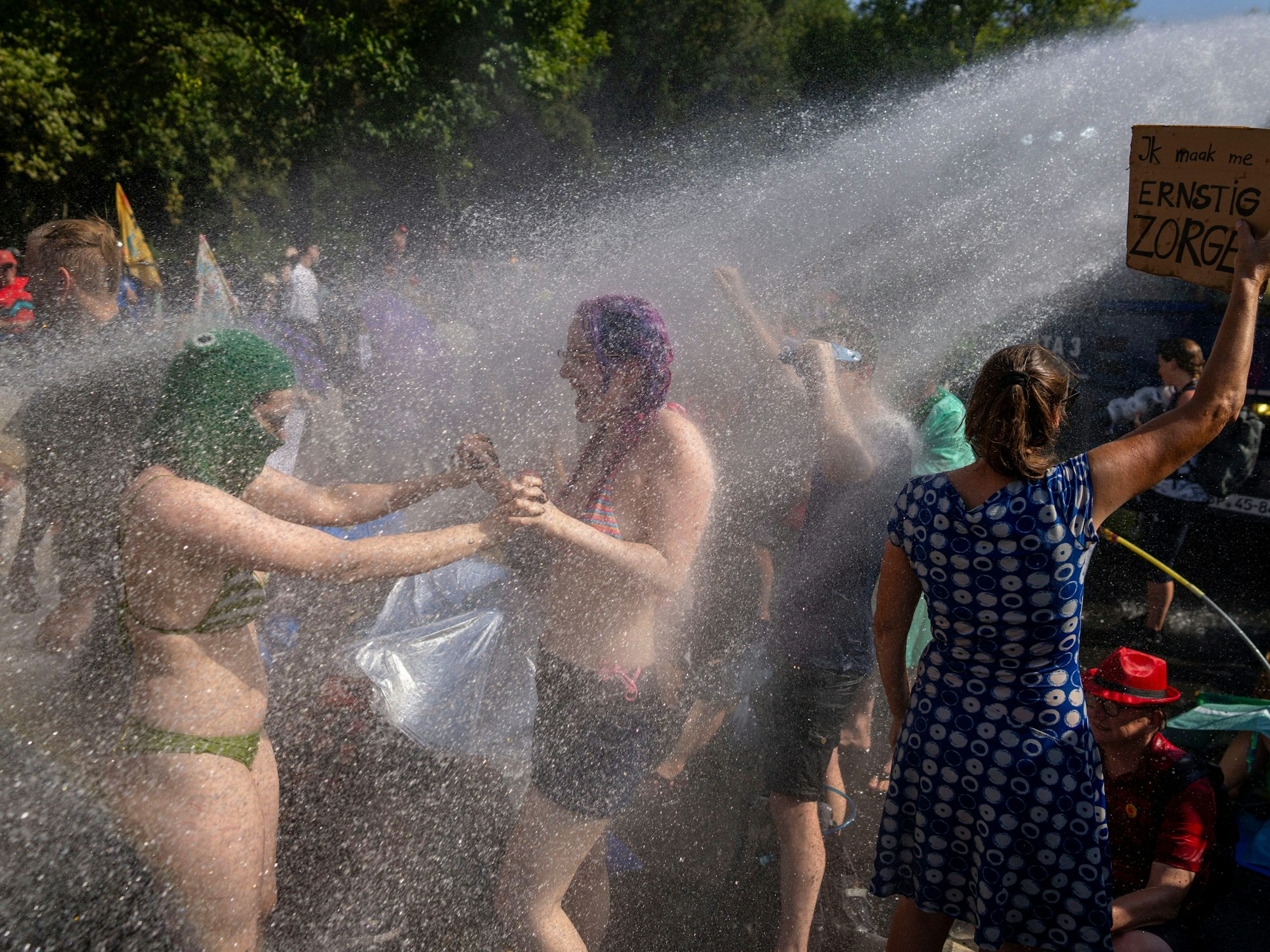 Klimaaktivistinnen tanzen am 9. September 2023 im Wasserstrahl eines Wasserwerfers der niederländischen Polizei während einer Klimaprotestaktion von Extinction Rebellion und anderen Aktivistinnen und Aktivisten in der Nähe des niederländischen Parlaments in Den Haag.