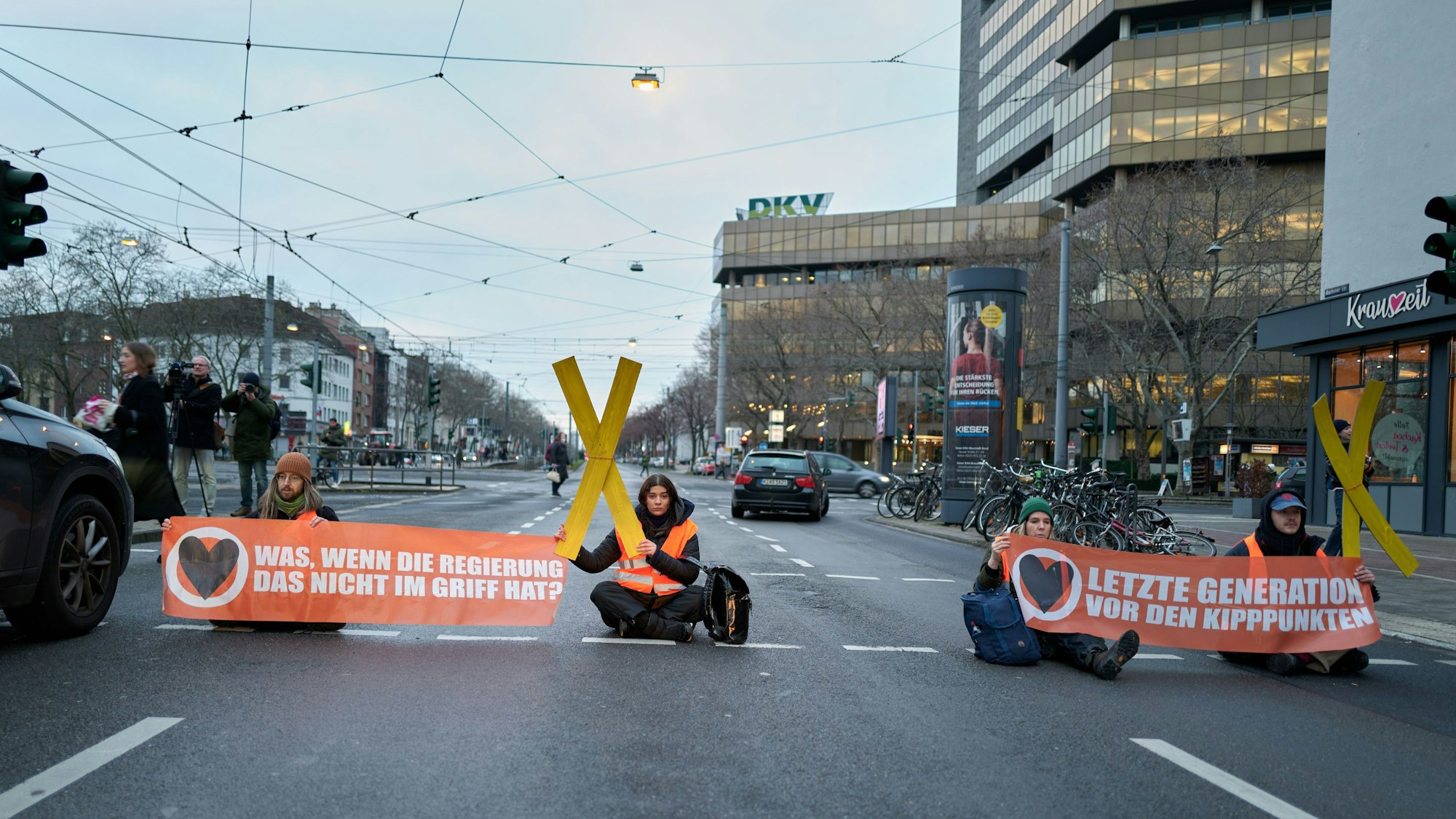 Aktivisten und Aktivistinnen der Letzten Generation sitzen bei einem Protest auf der Aachener Straße in Köln.