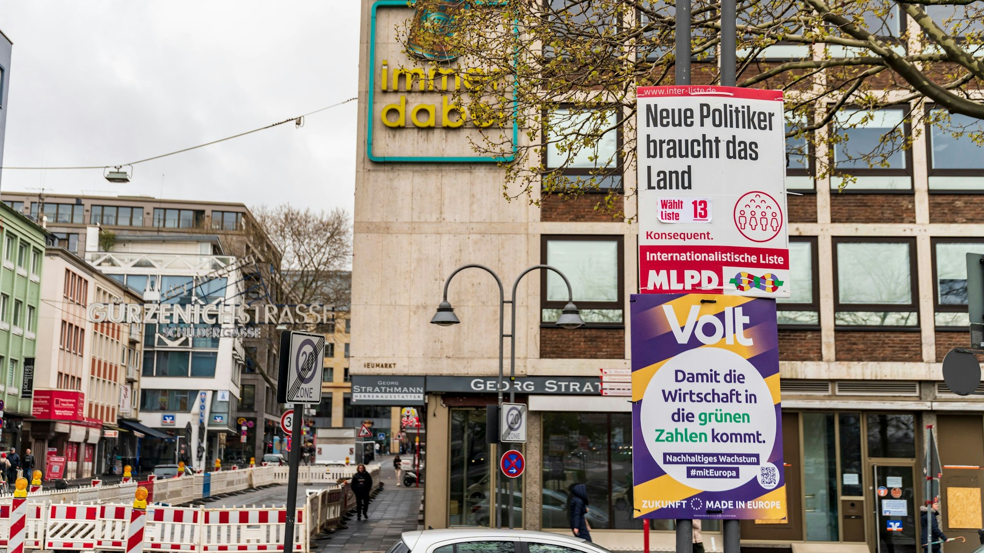 Wahlplakate von Volt und MLPD hängen an einer Straße in Köln an einem Schild.