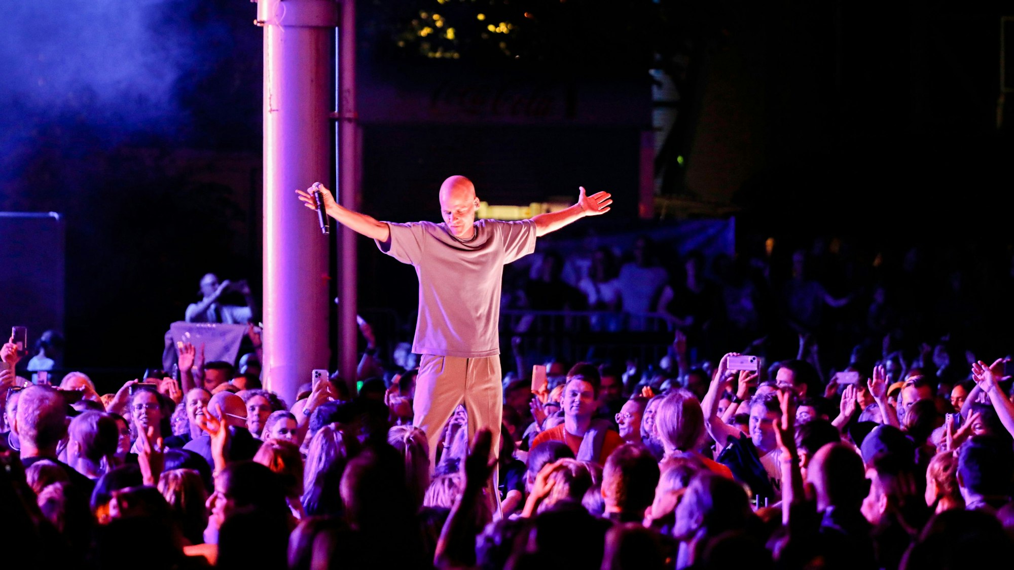 Oliver Niesen steht im Scheinwerferlicht mitten im Publikum und breitet seine Arme aus.