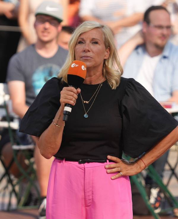 „Fernsehgarten“-Moderatorin Andrea Kiewel steht mit einem Mikrofon in der Hand auf der Bühne.