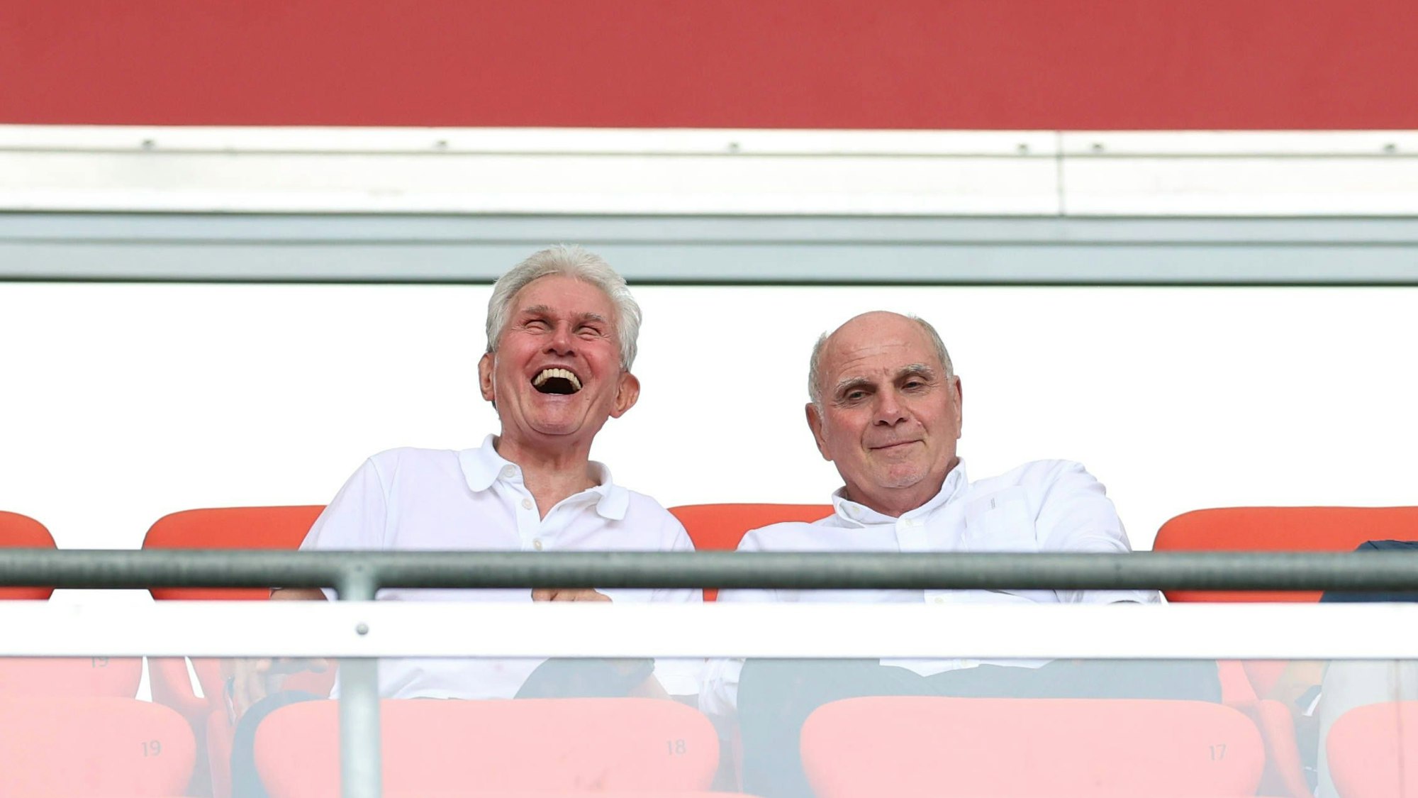 Jupp Heynckes sitzt auf der Tribüne neben Uli Hoeneß und lacht.