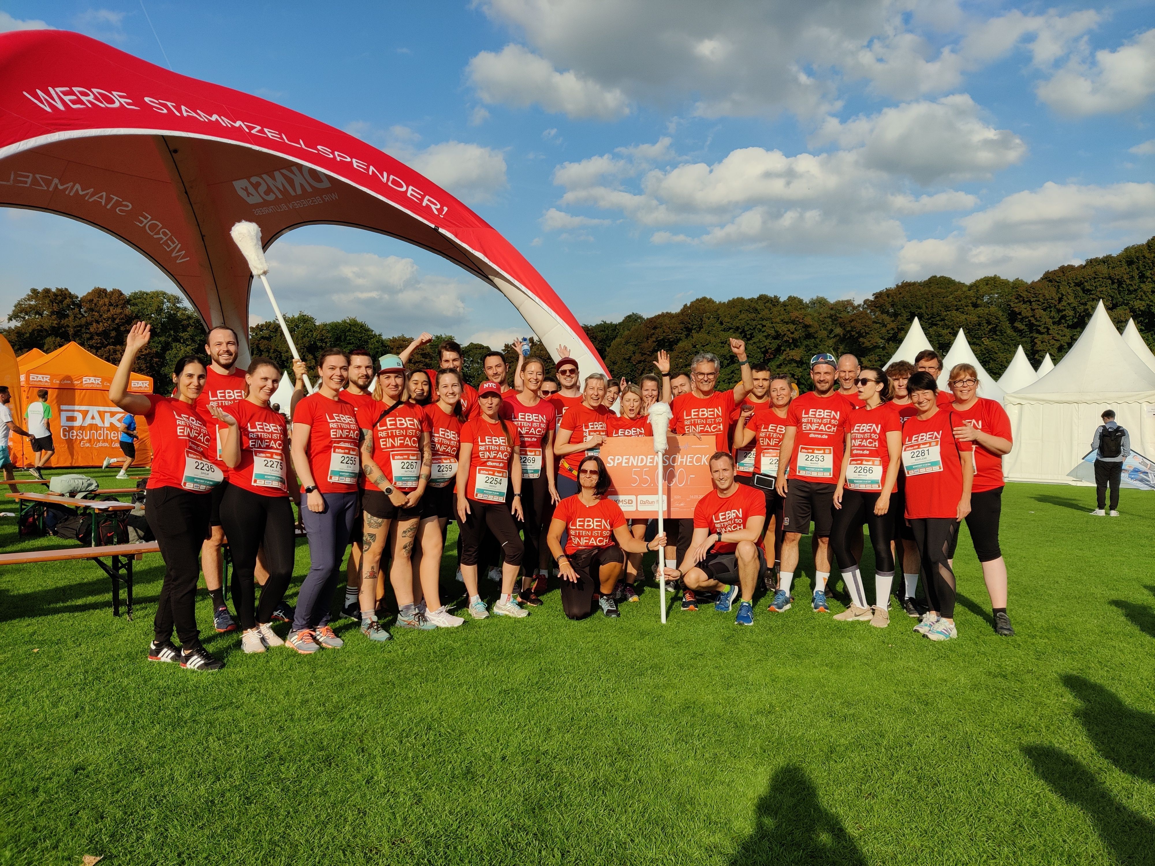Etwa 20 Menschen in roten Shirts haben sich für ein Gruppenfoto aufgestellt.