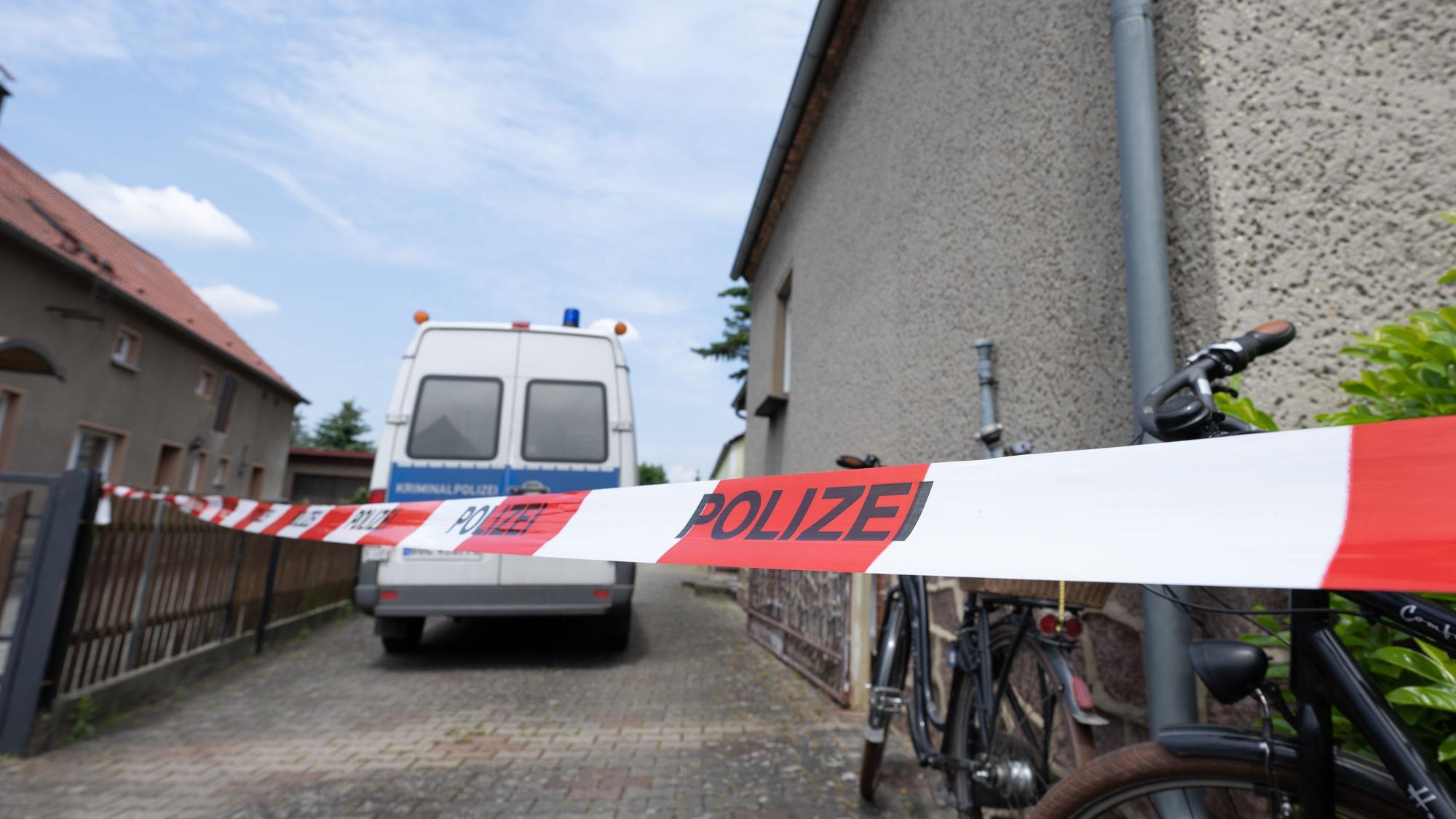 Ein Fahrzeug der Polizei steht in einer Hauszufahrt, die mit einem Flatterband abgesperrt ist.