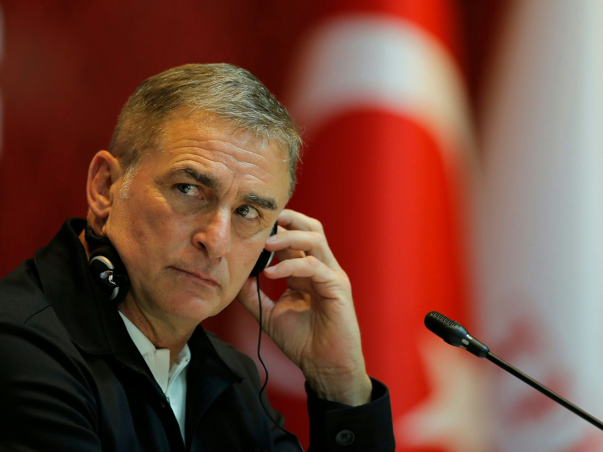 Stefan Kuntz trägt Kopfhörer bei einer Pressenkonferenz. Im Hintergrund ist die türkische Nationalflagge zu erkennen.