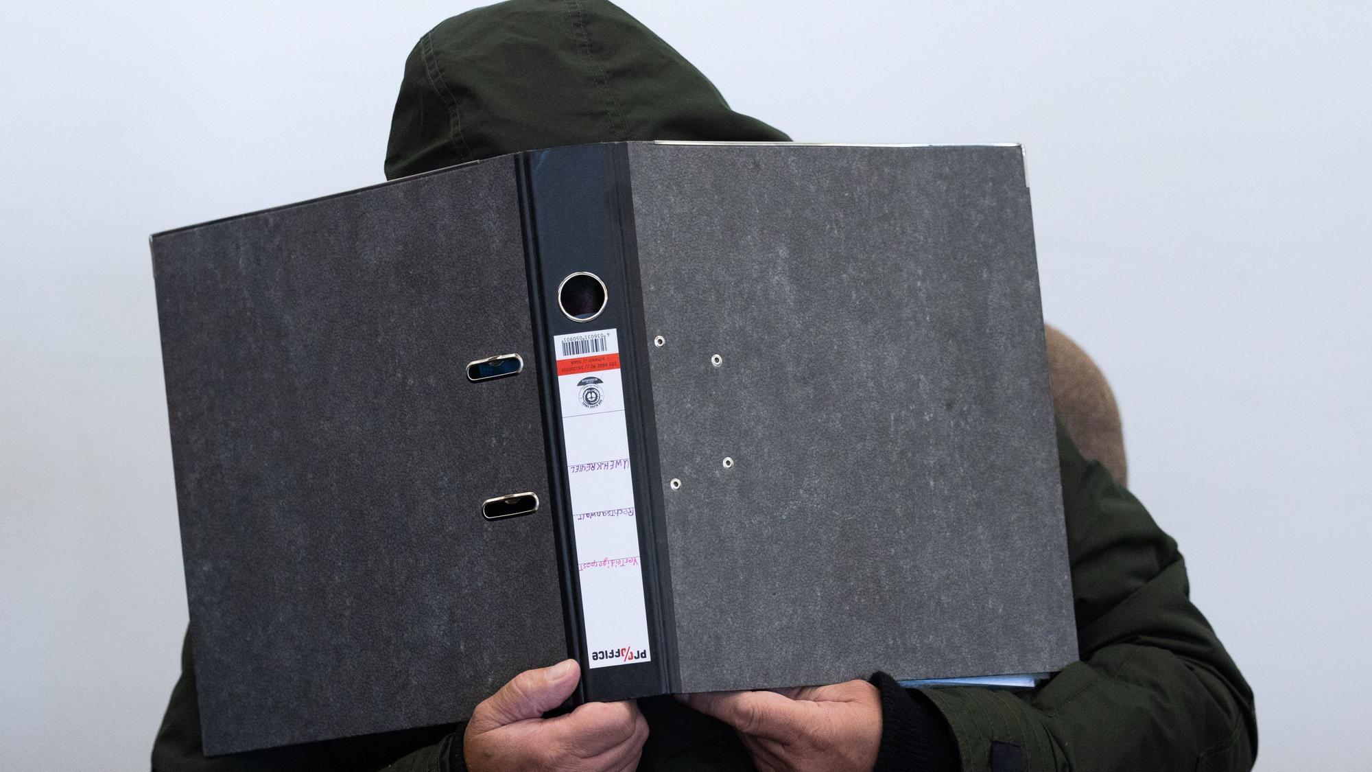 Der Angeklagte verdeckt mit einem Aktenordner sein Gesicht. Seit dem 4. September 2023 läuft im Landgericht Köln der Mordprozess im sogenannten Karnevalsmord.