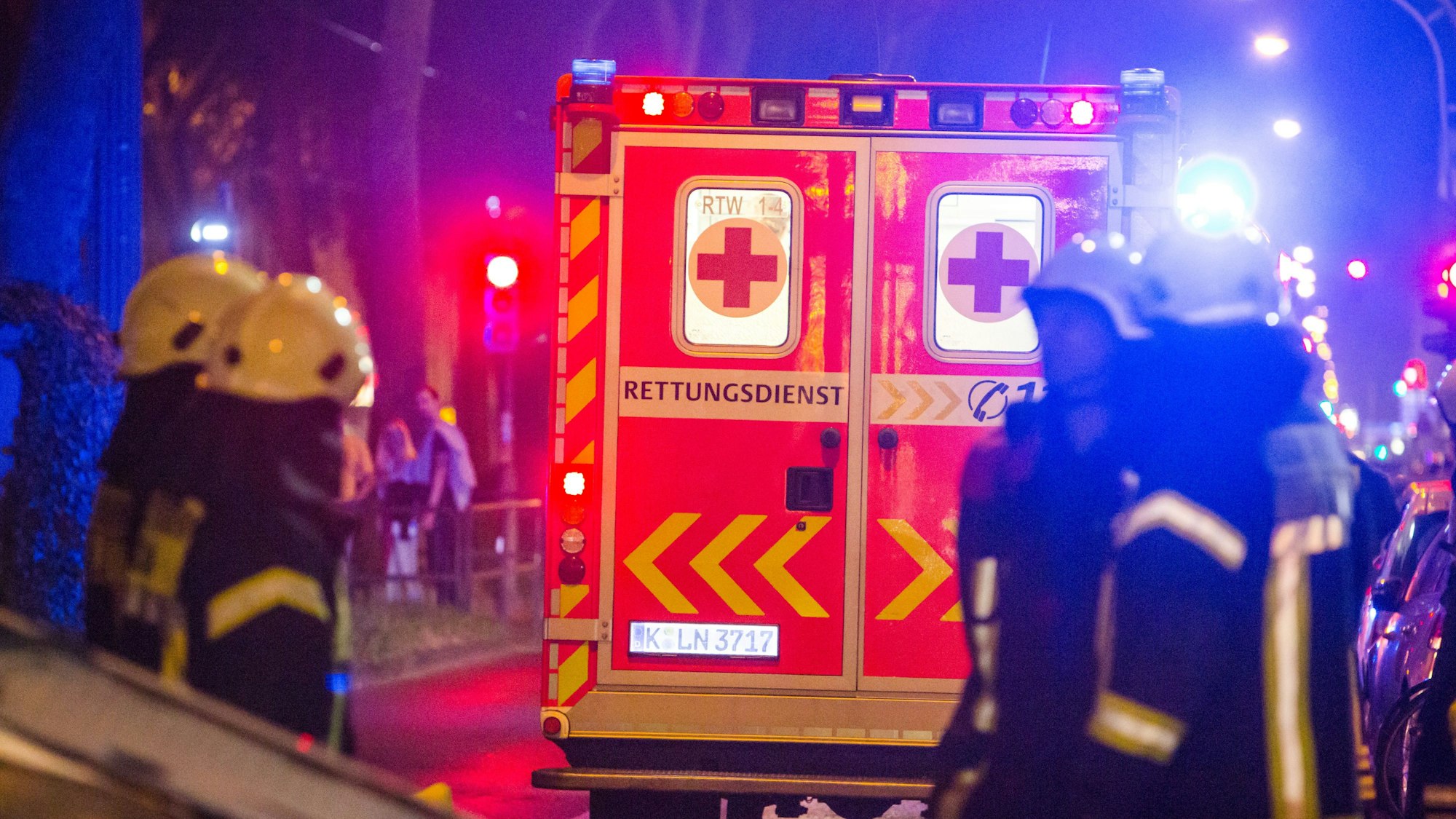 Ein Rettungswagen steht an einem Unfallort, davor Einsatzkräfte der Feuerwehr.