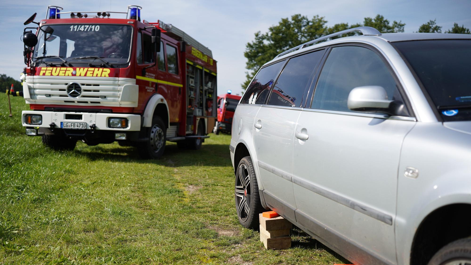 Der Unfallwagen, ein silberner Kombi, und ein Fahrzeug der Feuerwehr stehen am Unfallort.