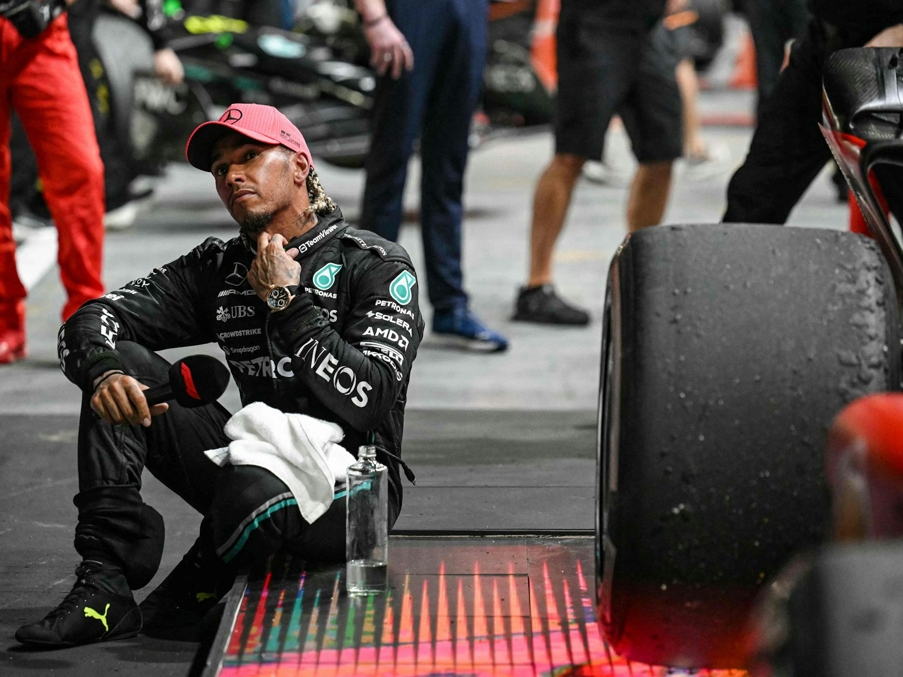 Lewis Hamilton sitzt mit einer Flasche Wasser an seinem Formel-1-Boliden.