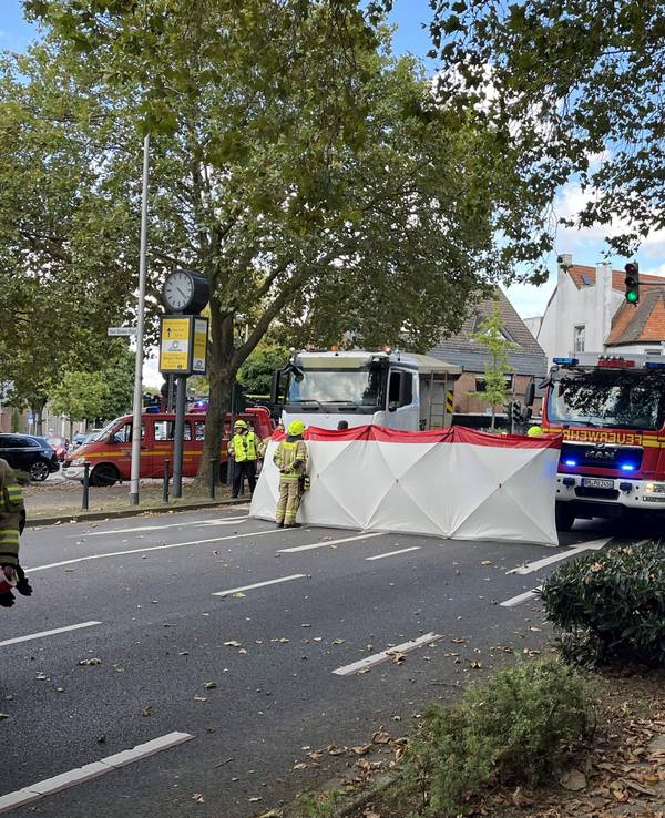 Einsatzfahrzeuge stehen neben einem Lkw auf einer Straße, davor ist ein mannshoher Sichtschutz aufgebaut.