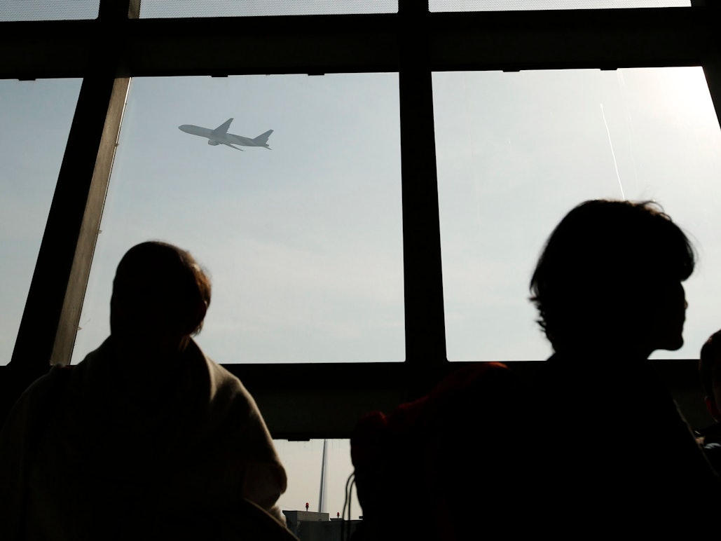 Ein Flugzeug ist durch ein Fenster zu sehen, während ausländische Touristen am Flughafen Suvarnabhumi in Bangkok, Thailand, am 24. Dezember 2014 Schlange stehen.
