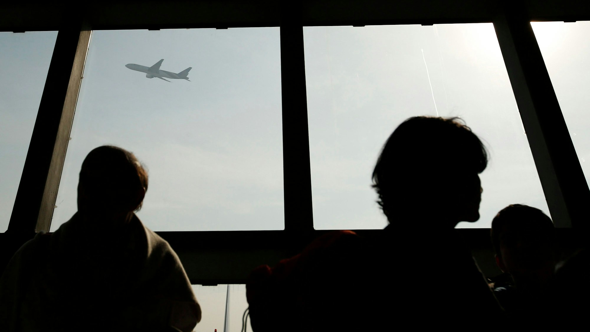 Ein Flugzeug ist durch ein Fenster zu sehen, während ausländische Touristen am Flughafen Suvarnabhumi in Bangkok, Thailand, am 24. Dezember 2014 Schlange stehen.
