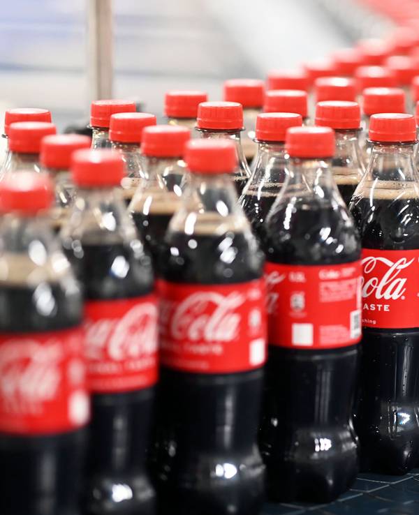 Abgefüllte 0,5 Liter Einweg Coca-Cola Flaschen werden über ein Förderband transportiert.