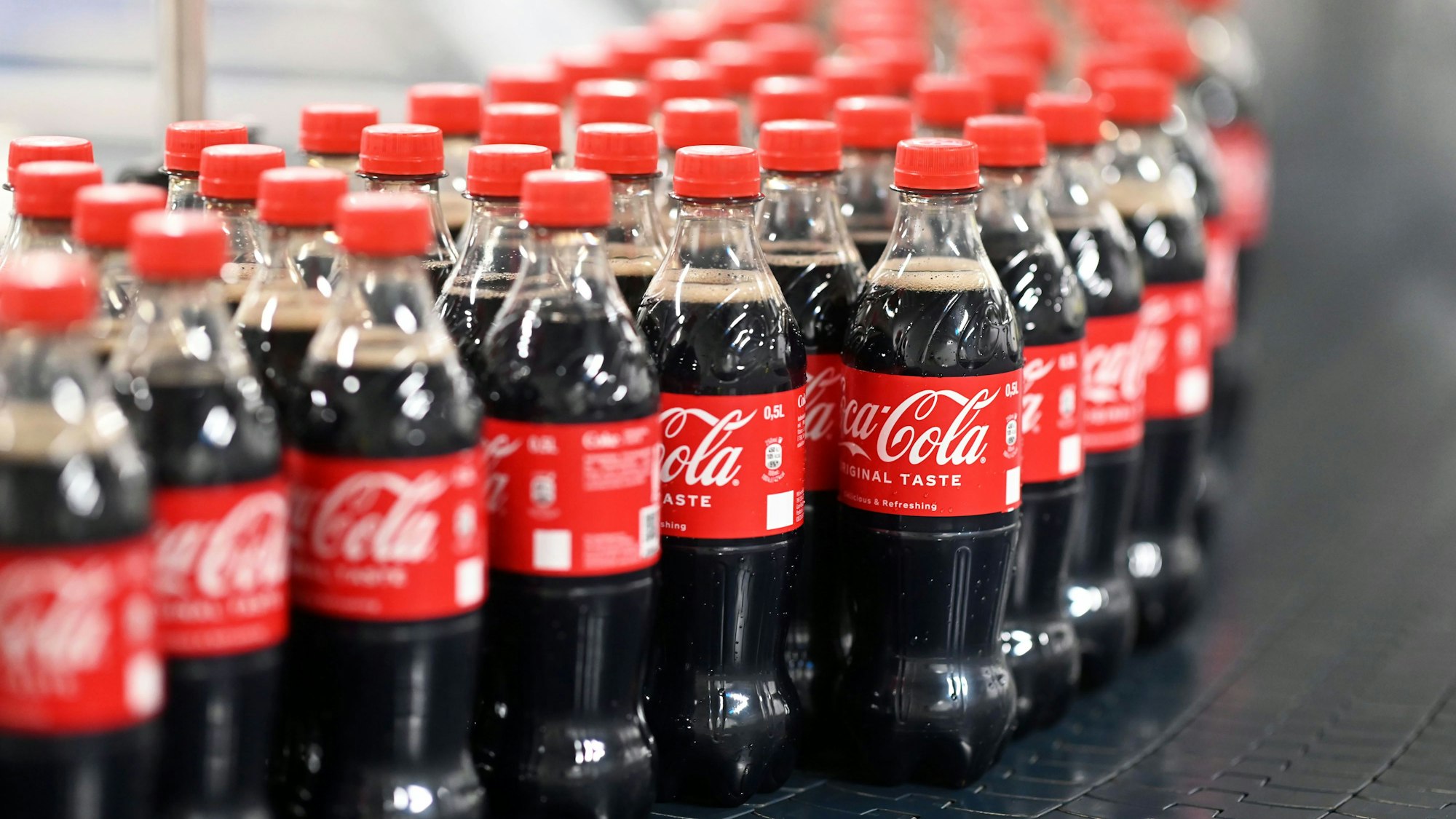 0,5-Liter-Einweg-Flaschen von Coca-Cola laufen im August 2023 über ein Förderband: Coca-Cola testet in Österreich eine Verpackungs-Alternative.