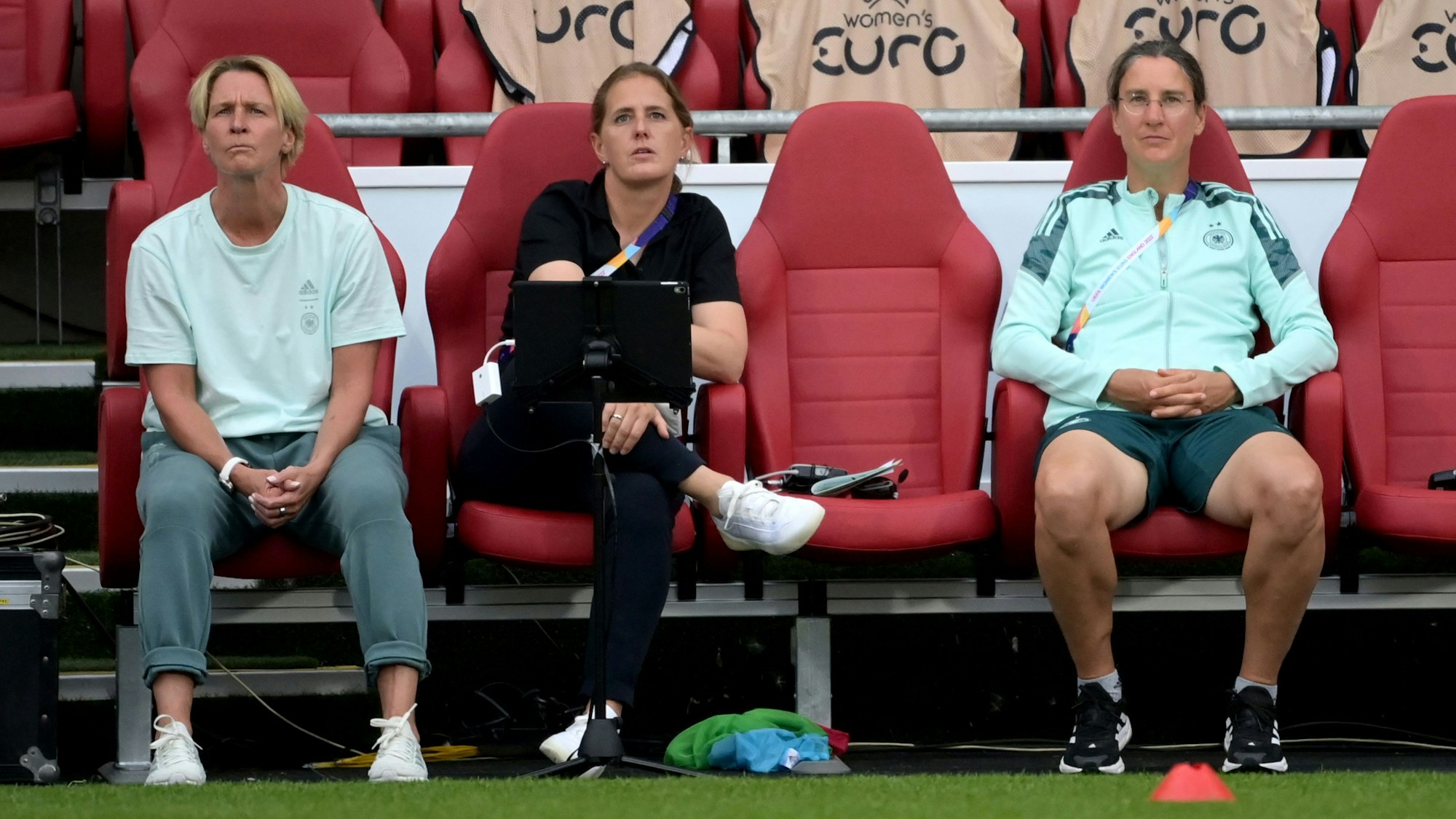 Bundestrainerin Martina Voss-Tecklenburg sitzt bei einem EM-Spiel neben ihrer Co-Trainerin Britta Carlson und Teampsychologin Birgit Prinz.