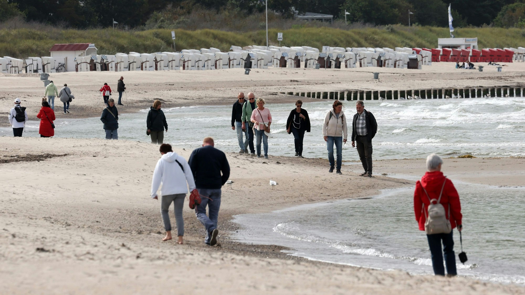 Spaziergänger sind am Ostseestrand in Warnemünde unterwegs.