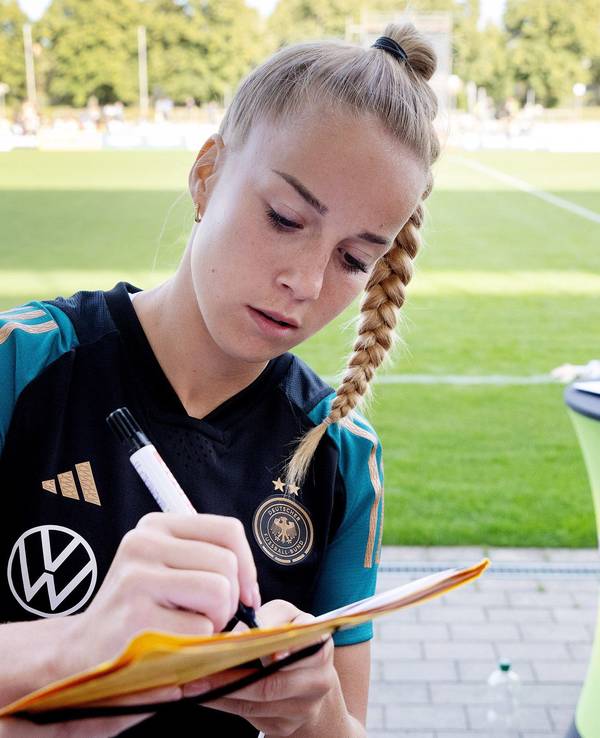Giulia Gwinn schreibt am Rande des DFB-Trainings Autogramme.
