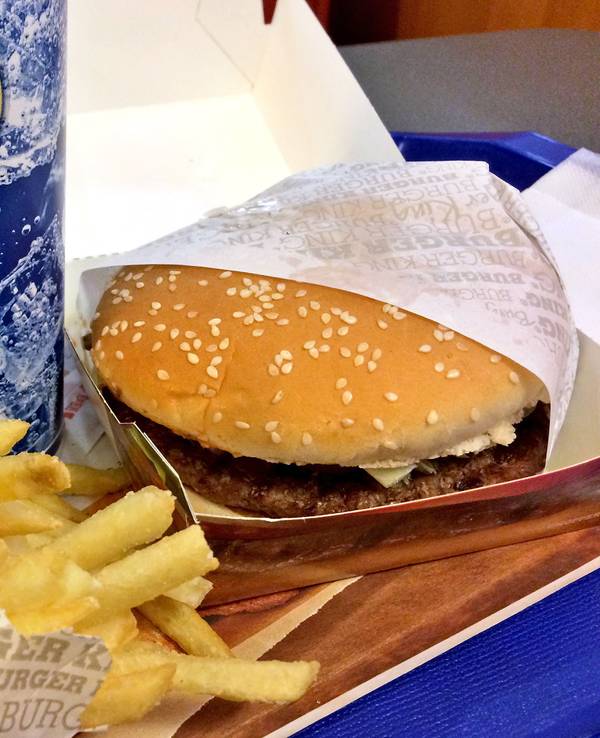 Ein Burger liegt mit Pommes und Getränk bei Burger King auf einem Tisch.