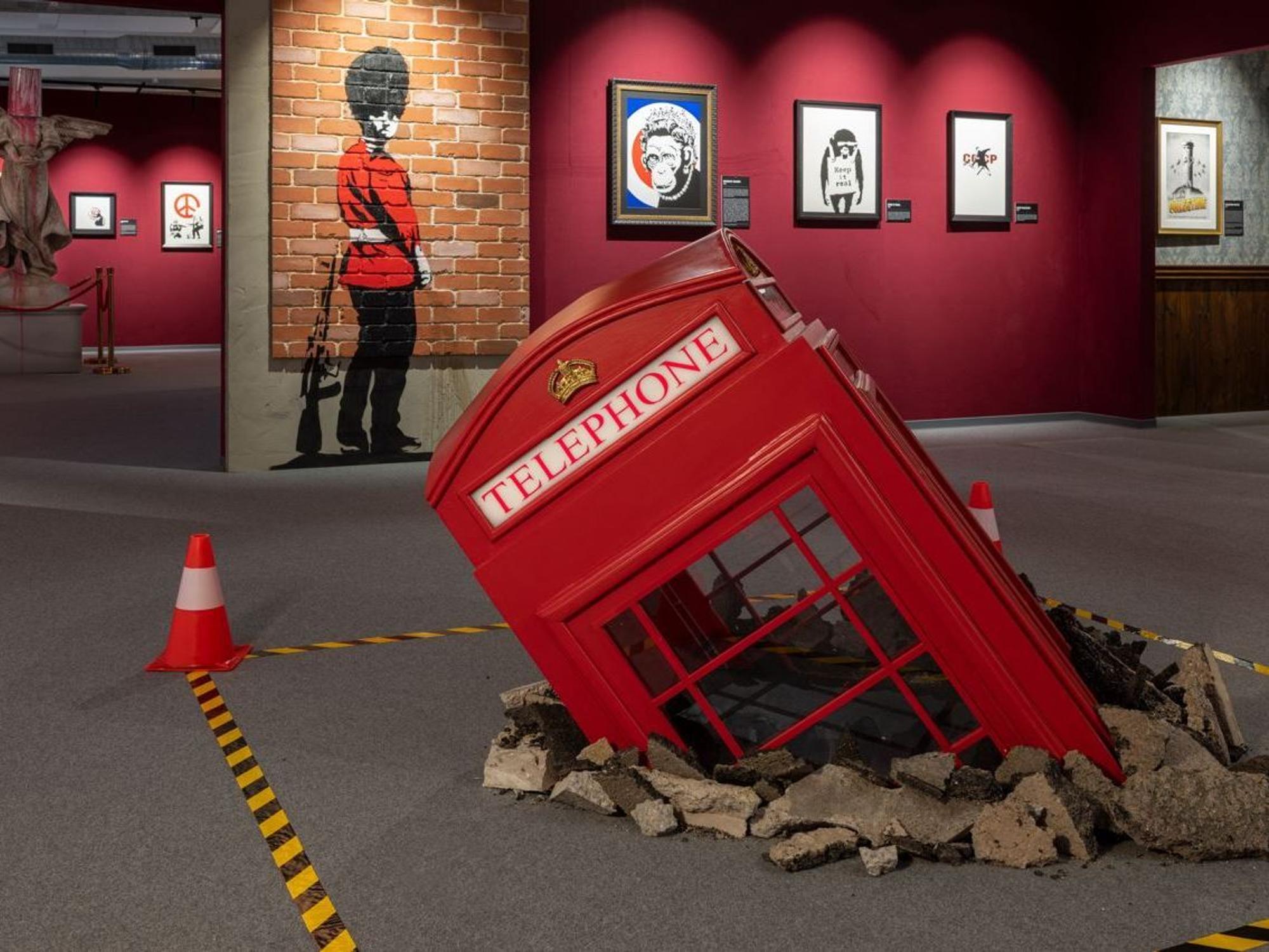 Eine umgestürzte Telefonzelle, die im Boden versinkt, stellt ein Highlight der neuen Kunstausstellung in Köln dar.