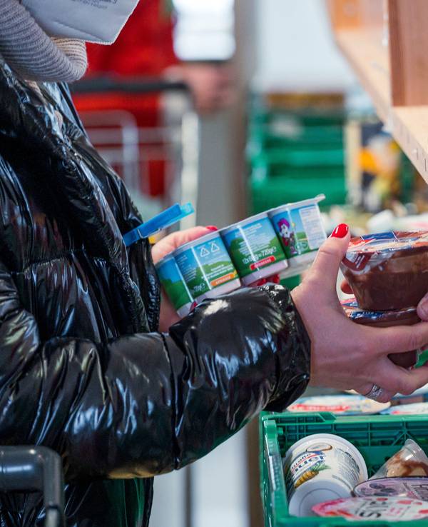 Eine Kundin kauft Joghurt und Pudding ein.
