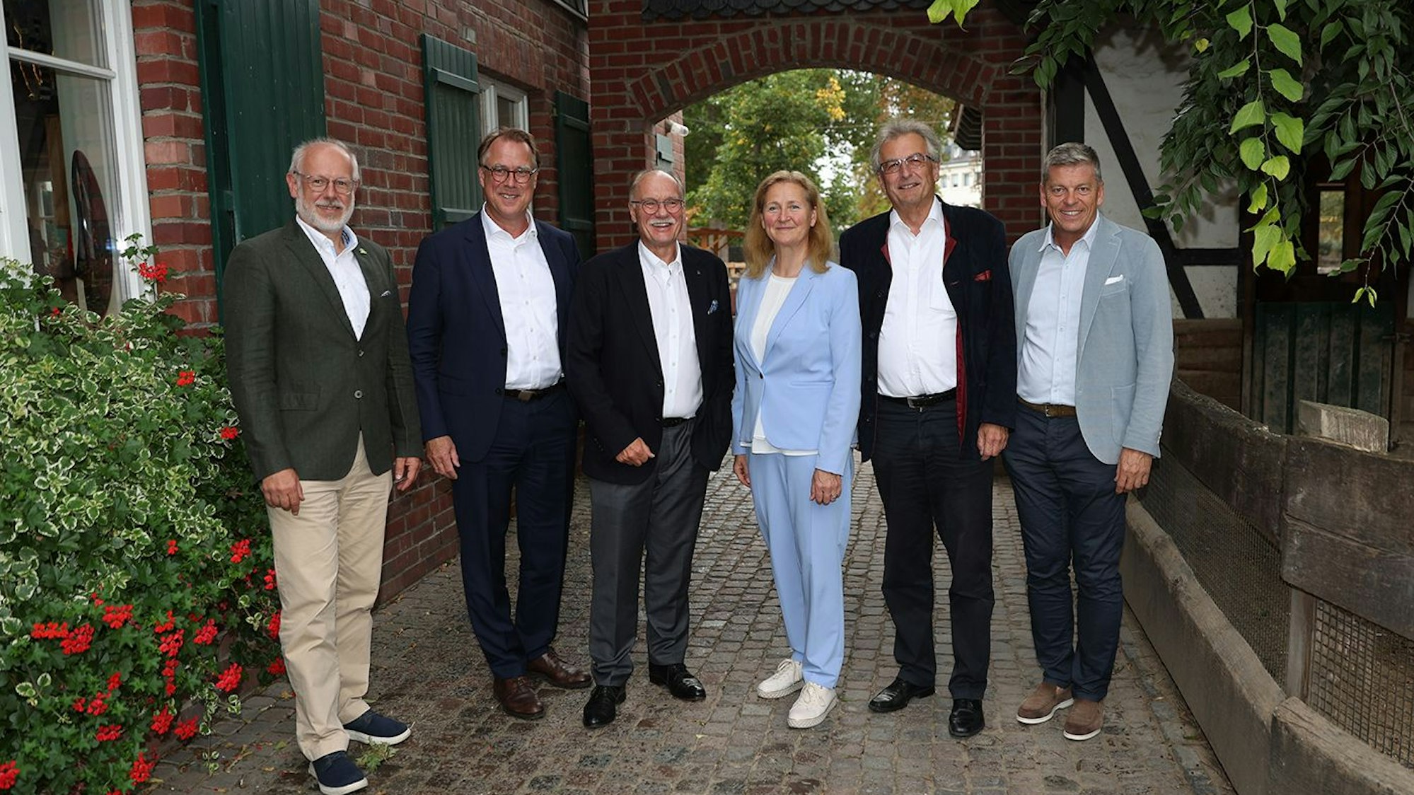 Fünf Männer und eine Frau schick gekleidet auf einem Gruppenfoto.