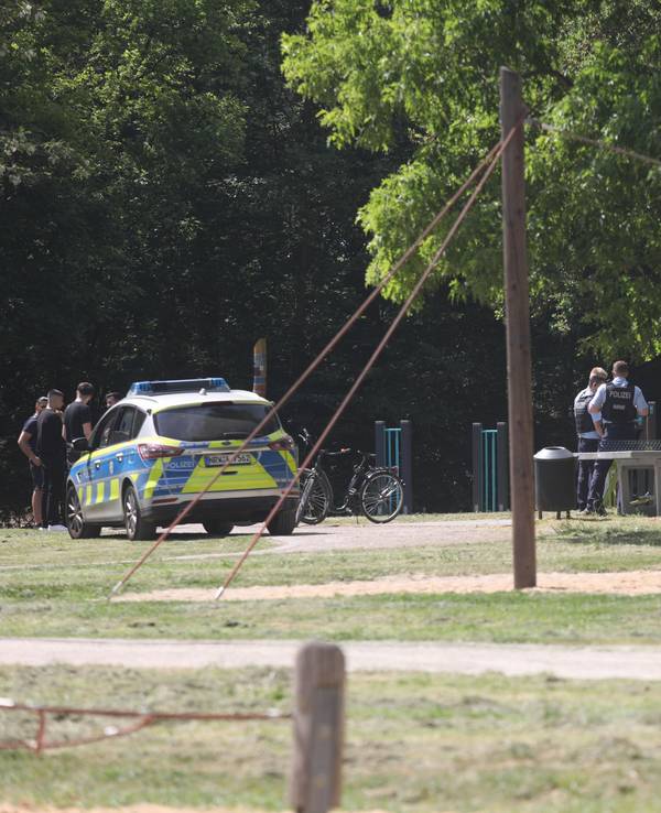 Ein Streifenwagen steht auf einem Spielplatz, auf dem sich auch mehrere Einsatzkräfte der Polizei befinden.