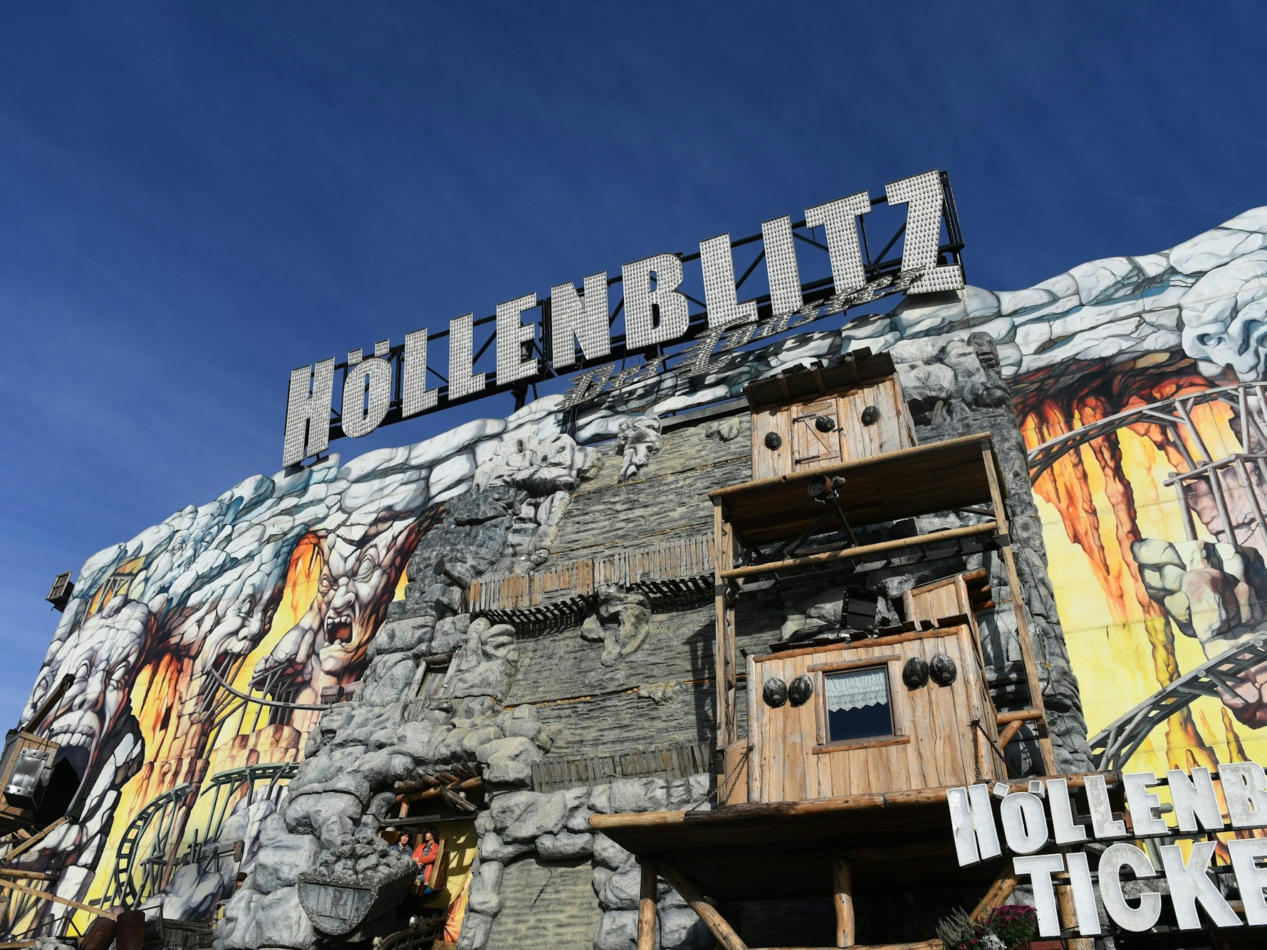 Blauer Himmel strahlt über dem Fahrgeschäft „Höllenblitz“ auf dem Münchner Oktoberfest.