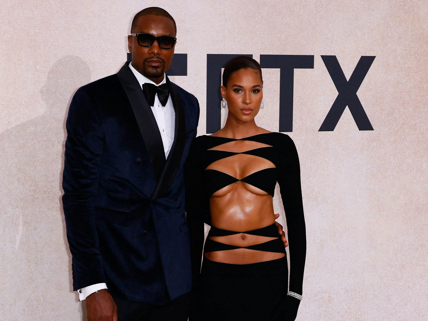 Serge Ibaka und Cindy Bruna stehen auf dem roten Teppich und posieren. Er trägt einen Anzug und eine Sonnenbrille, sie ein sehr luftiges Oberteil.