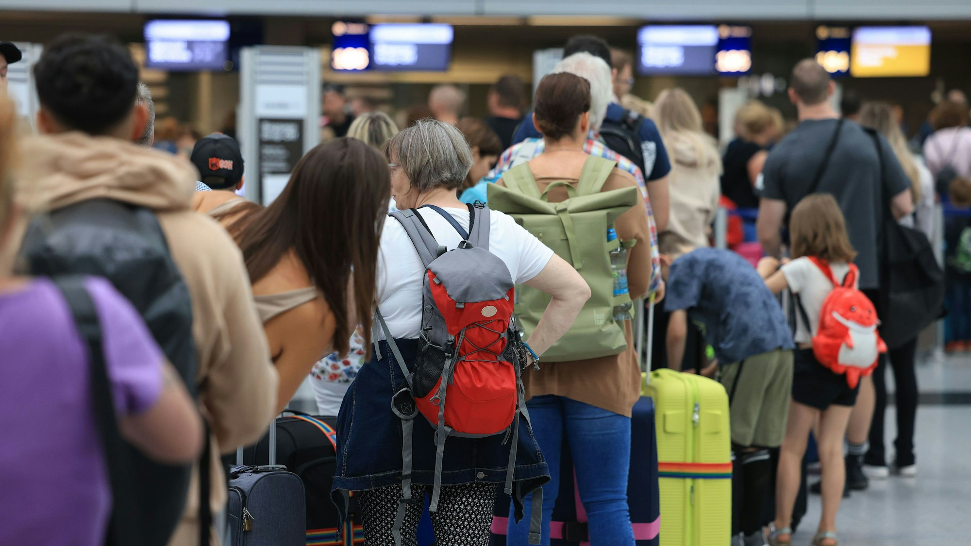 Reisende stehen am Flughafen Düsseldorf in einer Warteschlange.