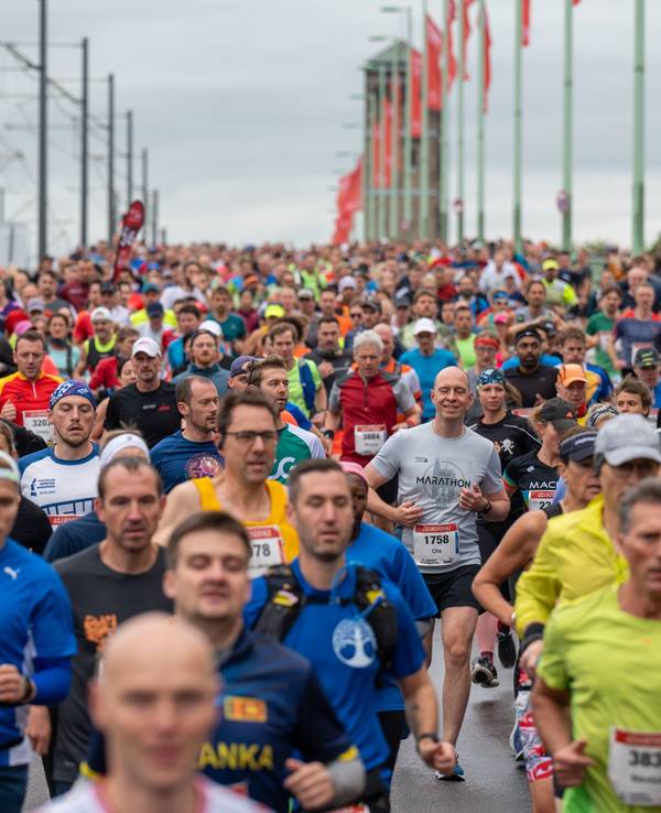 Massen an Läuferinnen und Läufer rennen über eine Brücke.