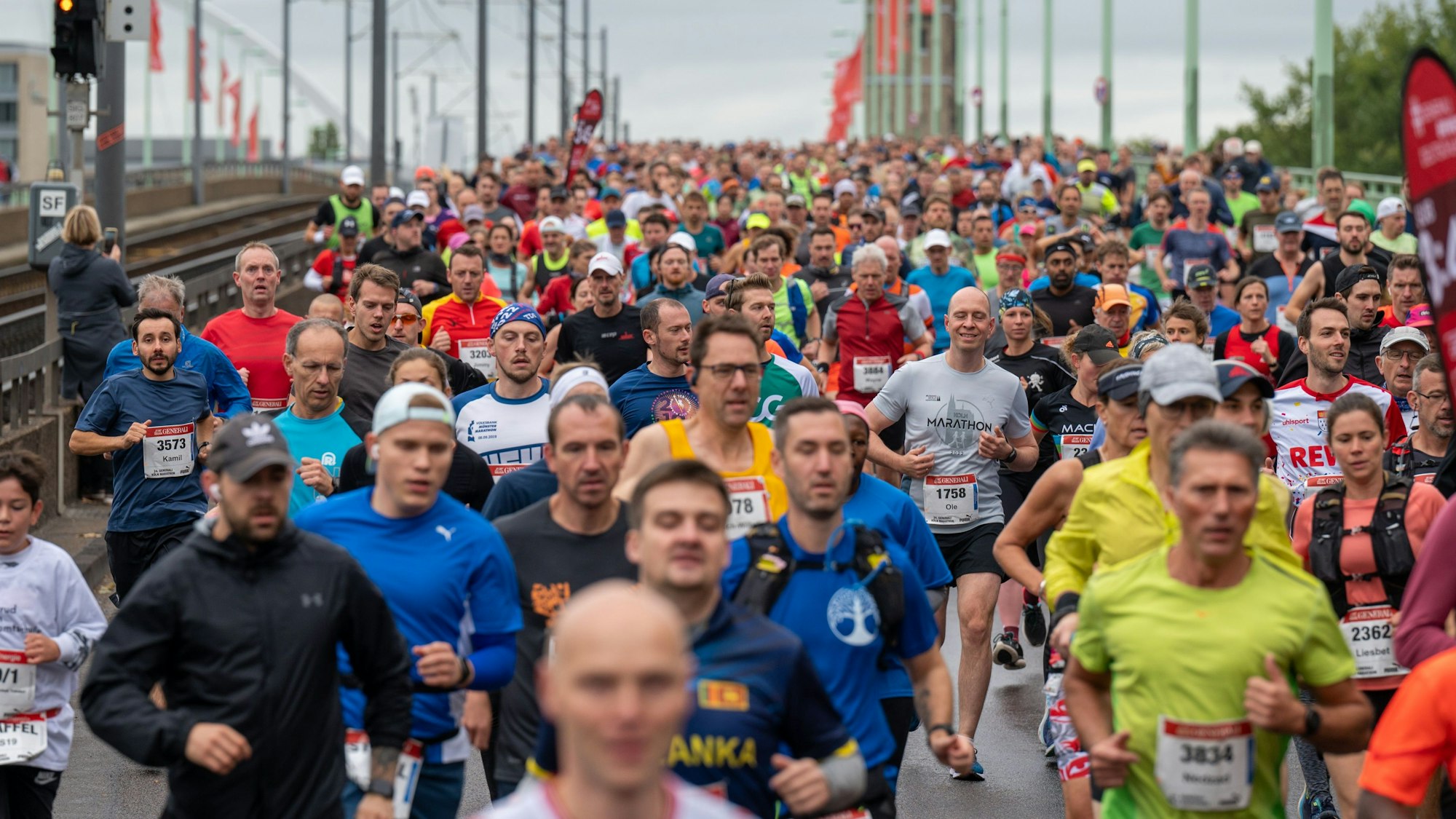 Massen an Läuferinnen und Läufer rennen über eine Brücke.
